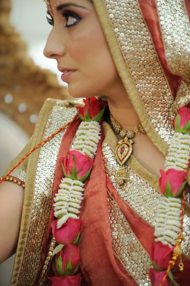 Woman in traditional attire adorned with floral garlands and intricate jewellery.