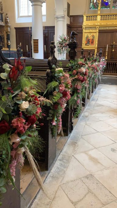 Decorative floral arrangements adorn church pews, adding colour to the interior.