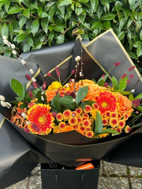Vibrant bouquet featuring orange and yellow flowers with green foliage.