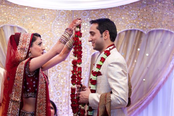 Bride and groom exchanging floral garlands in a festive wedding setting.