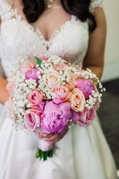 Bridal bouquet featuring pink and purple roses, peonies, and baby’s breath.