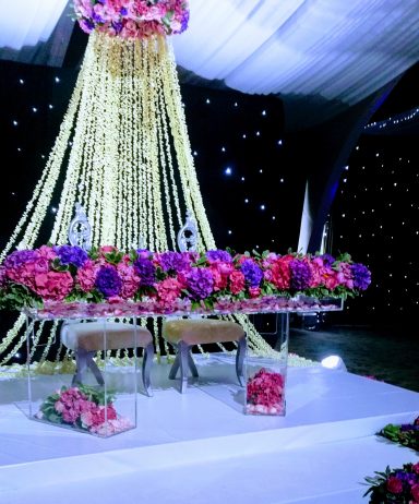 Decorative stage setup with floral arrangements and elegant drapery.