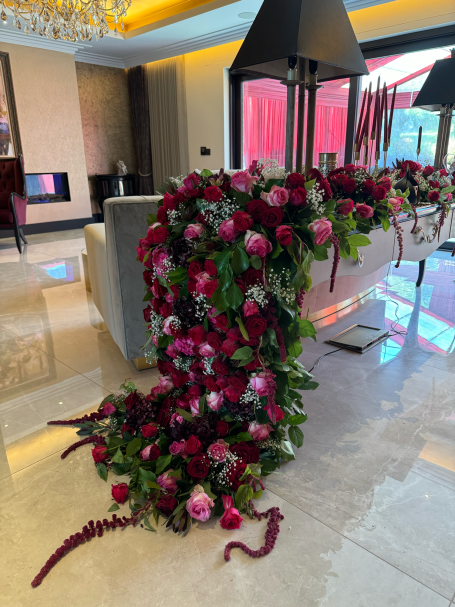Luxurious floral arrangement with red and pink flowers cascading over a modern table.