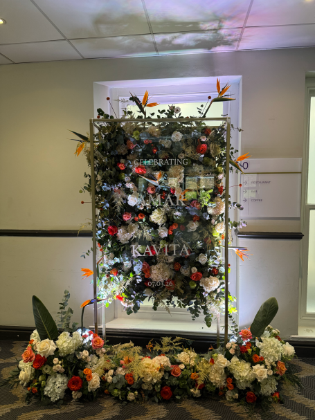 A floral arrangement on a decorative stand, featuring vibrant flowers and greenery.