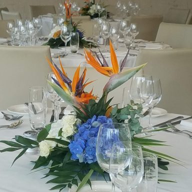 Vibrant floral arrangement with tropical flowers on a dining table setting.