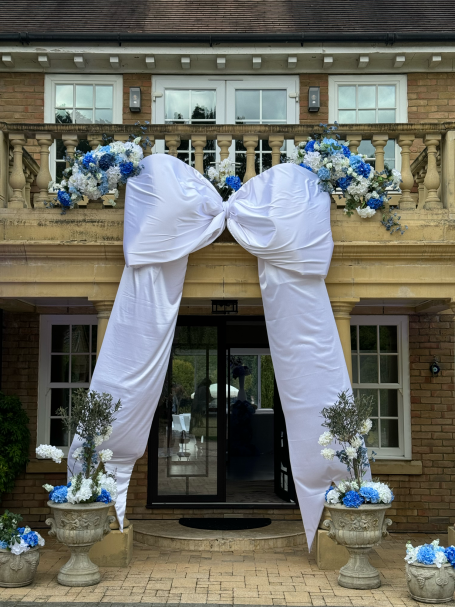 Large white bow with blue flowers adorning a doorway and entrance.