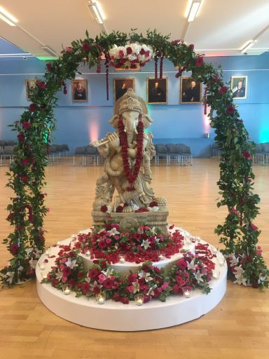 A statue adorned with flowers and greenery in a decorated space.