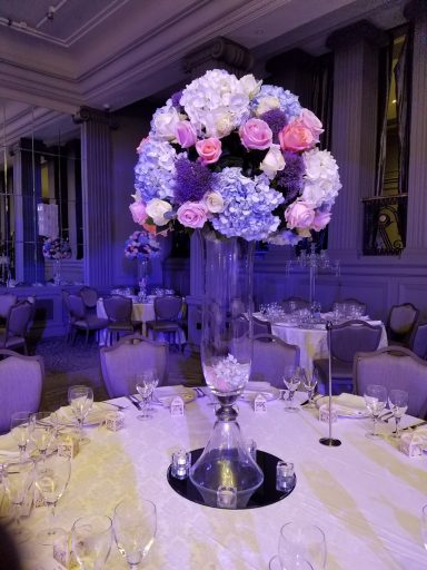 Elegant flower arrangement in a tall vase on a decorated dining table.