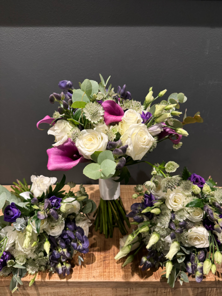 A bouquet of white and purple flowers, arranged elegantly with greenery.