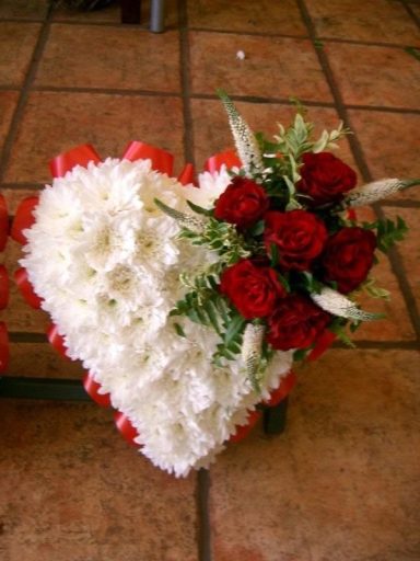 A heart-shaped floral arrangement with red roses and white flowers.