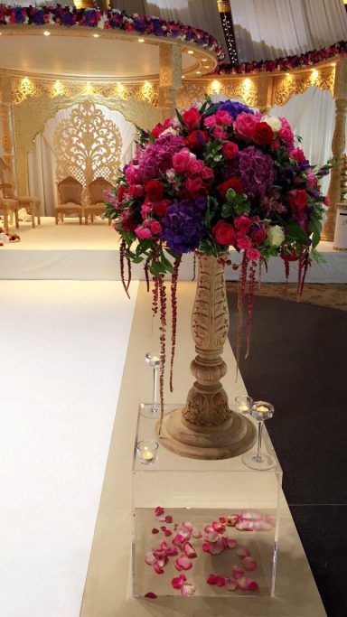 A decorative floral arrangement in vibrant pink and purple hues on a pedestal.