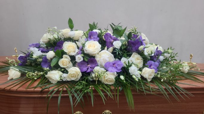 Floral arrangement with white and purple flowers on a wooden surface.