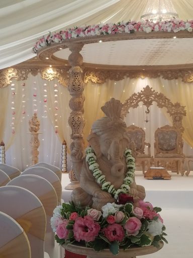 Ornate wedding altar with a statue of Ganesha surrounded by floral arrangements.