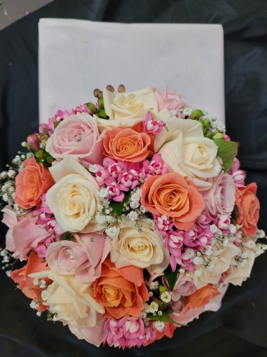 A bouquet of pink and orange roses with white flowers and greenery.