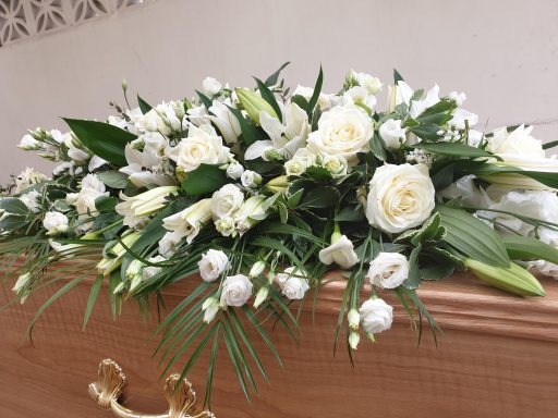 Arrangement of white flowers on a wooden casket.