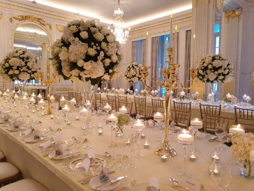 Elegant banquet setup with tall floral arrangements and candles on each table.