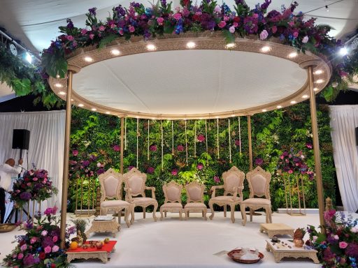 Elegant stage setup with floral decor, chairs, and a vibrant green backdrop.