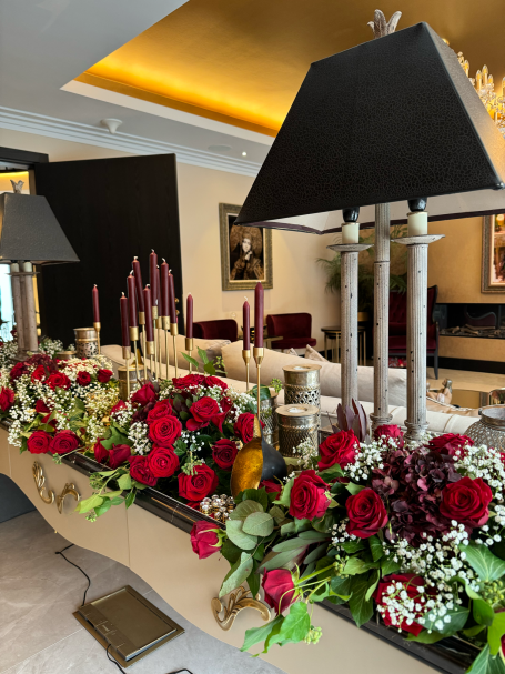 A decorative table arrangement with red roses, candles, and elegant lamps.