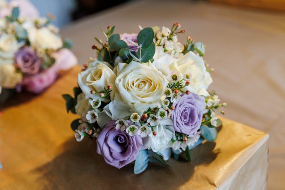 A bouquet of white and lavender roses with green foliage and small white flowers.