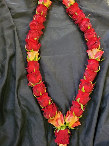 A vibrant floral necklace made of red roses and light pink blooms.