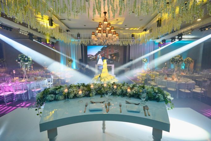 Elegant banquet setup with floral decor and dramatic lighting, featuring a central stage.