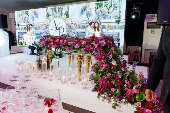 Luxurious table adorned with vibrant flowers and candles, set against a festive backdrop.