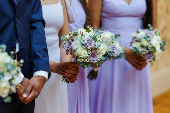 Bridesmaids in lavender dresses holding bouquets of flowers.