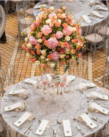 Elegant table setting with a tall floral arrangement in soft pinks and whites.