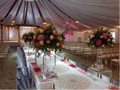 Elegant wedding venue with floral centrepieces and a decorated aisle.