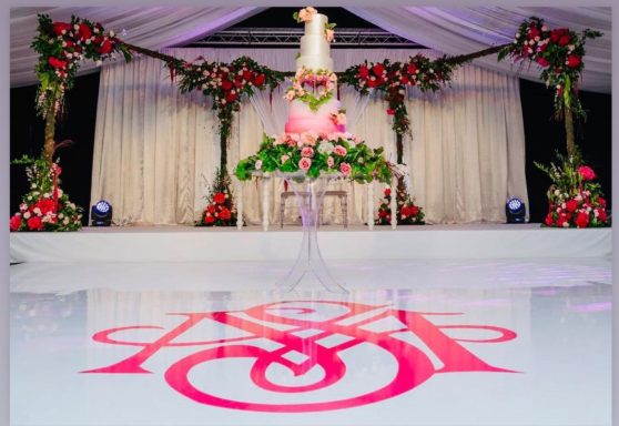 Elegant wedding setup with floral decorations and a cake displayed on a glass table.