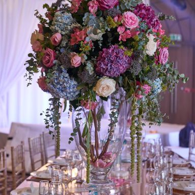 A tall vase filled with a vibrant bouquet of pink and blue flowers.
