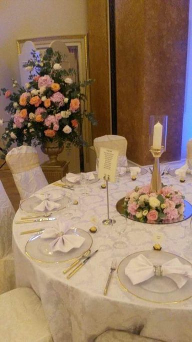 A beautifully set dining table with floral arrangements and candles.