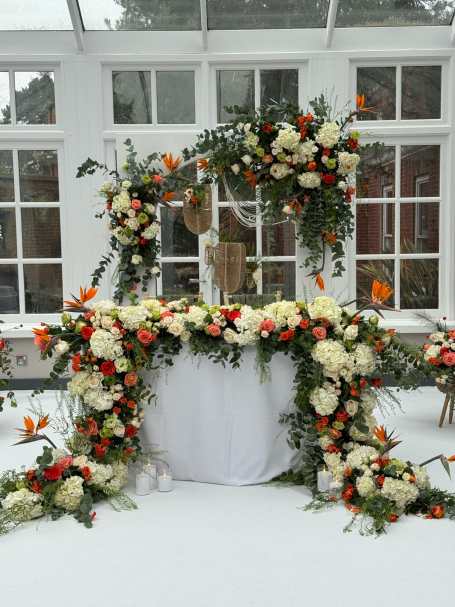 A floral arrangement of white and orange flowers decorates a table in a snowy setting.