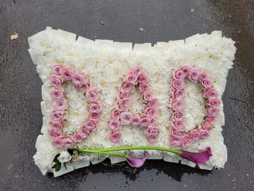 Floral cushion shaped with white flowers and pink roses spelling "DAD".